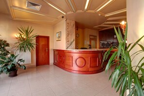 A reception area with a marble counter, a clock, and a door. - Central Plaza Hotel (Sofia)