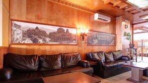 Eine Lobby mit Ledersofas, Holztischen und zwei großen Bildern in Rahmen an der Wand.