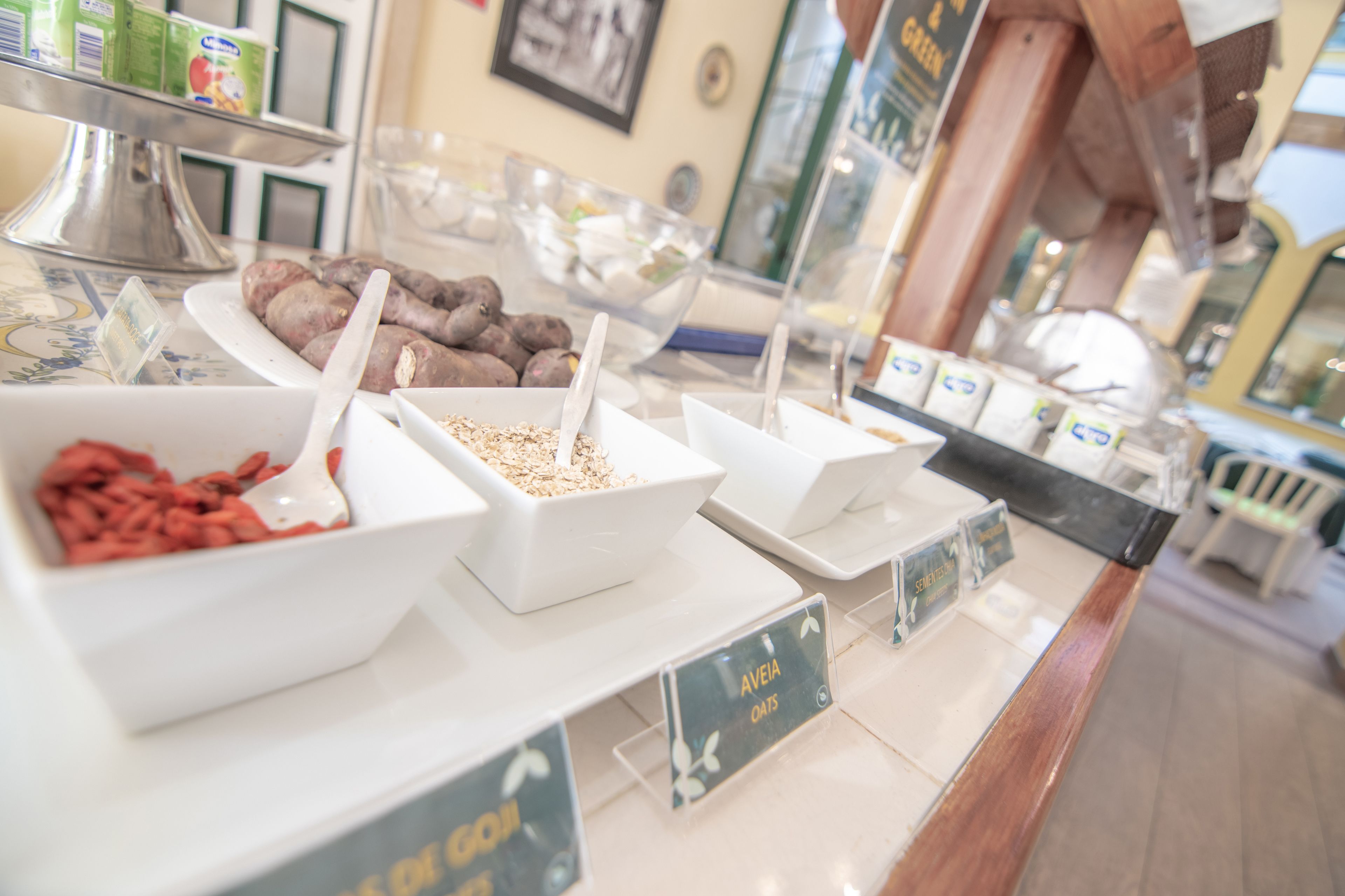Un bufé de desayuno con secciones de alimentos identificadas, incluyendo avena y una variedad de otros productos.