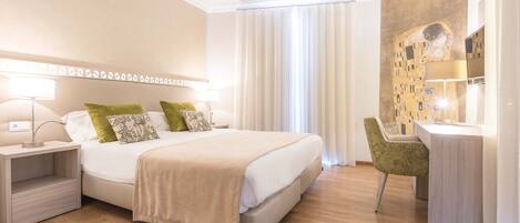 Una habitación de hotel moderna con una cama grande, mesitas de noche, un escritorio y una silla.