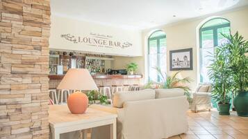 A lounge bar area with a stone wall, a table with a lamp, a sofa, and potted plants.