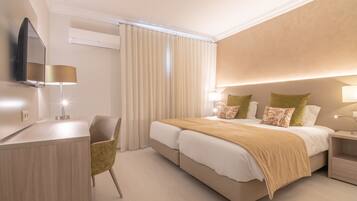 Quarto de hotel moderno com uma cama grande, mesas de cabeceira, uma escrivaninha e uma cadeira.