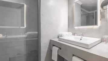 Een moderne badkamer met een douchecabine van glas, een grote spiegel en een wastafelmeubel met een wastafel.
