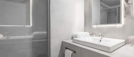 A modern bathroom with a glass shower enclosure, a large mirror, and a vanity with a sink.