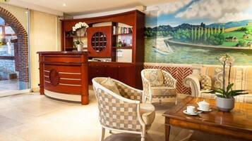 A lobby with a reception desk, a sofa set, and a mural of a river landscape.