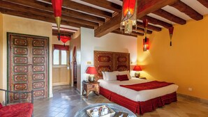 Une chambre d’hôtel avec un grand lit, une literie rouge, un plafond en bois et une porte de style traditionnel.