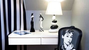 Een bureau met een lamp, twee beeldjes, een stapel stenen en een stoel met een grafisch ontwerp.