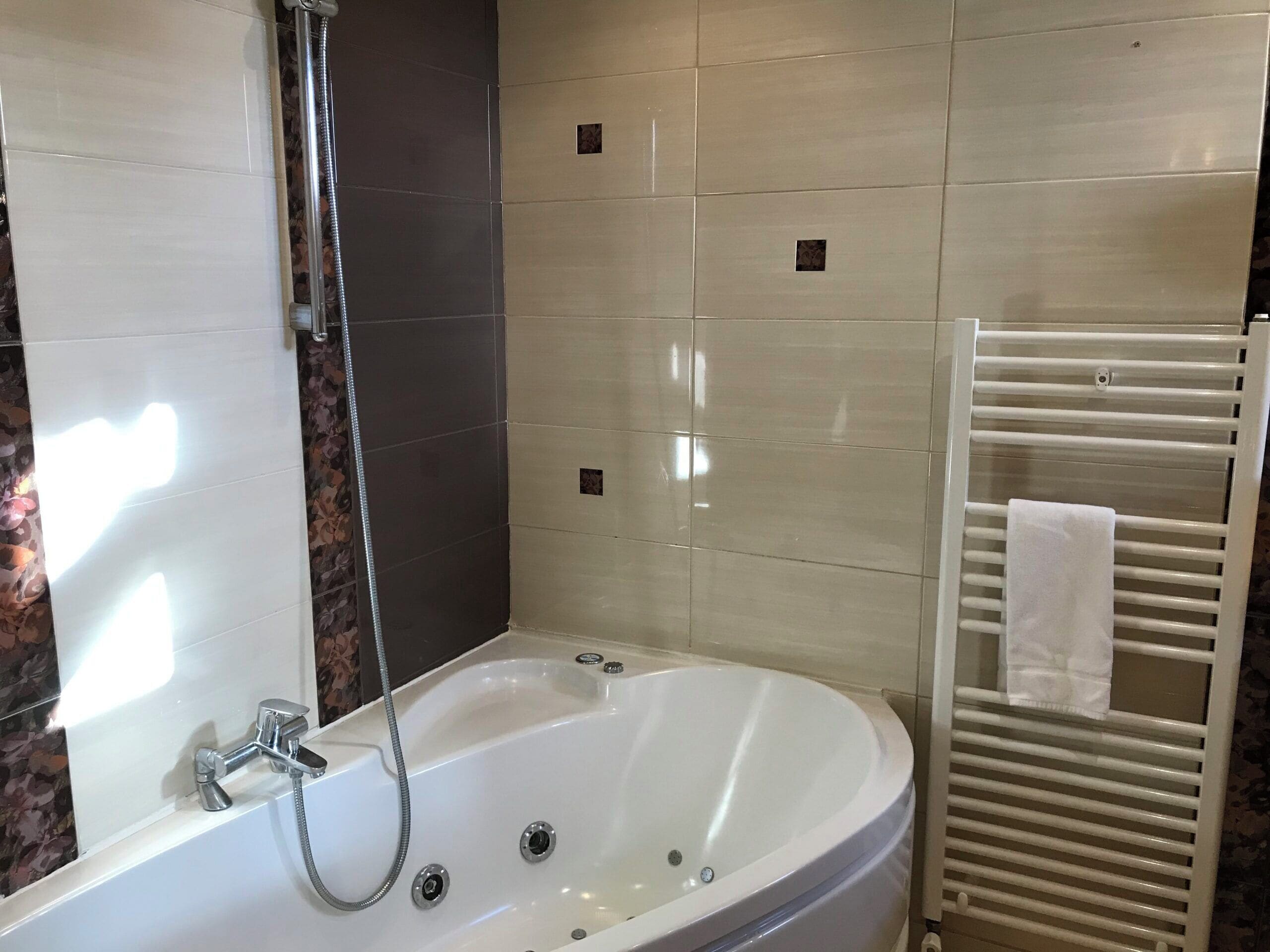 A modern bathroom with a freestanding bathtub, a glass-enclosed shower, and a white towel rack.