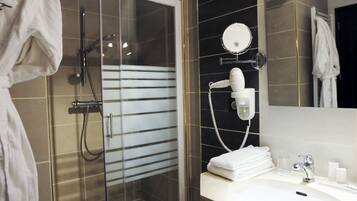 Ein modernes Badezimmer mit einer gläsernen Duschkabine, einem Waschtisch inklusive Spiegel und einem Handtuchhalter.