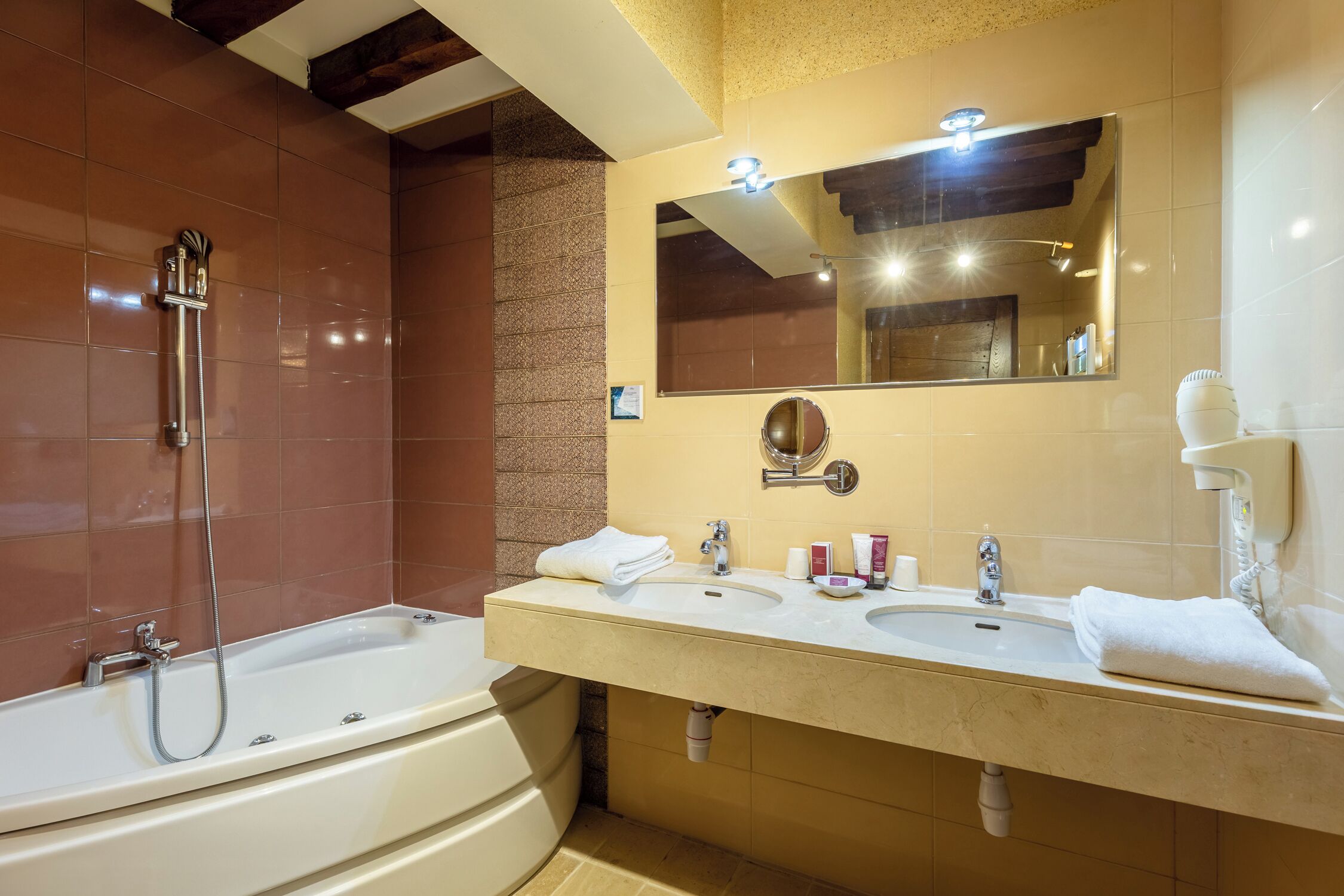 A modern bathroom with a bathtub, two sinks, a large mirror, and a towel rack.
