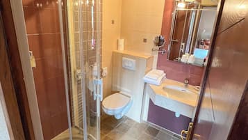 Une salle de bain avec une douche à parois de verre, des toilettes et un lavabo avec un miroir au-dessus.