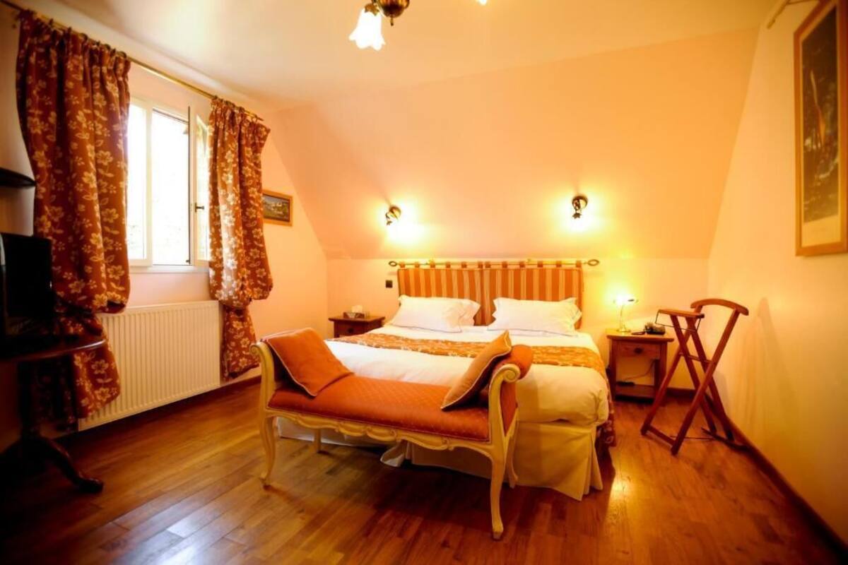 Un dormitorio con cama doble, una mesita de noche, una silla, un radiador y una ventana con cortinas.