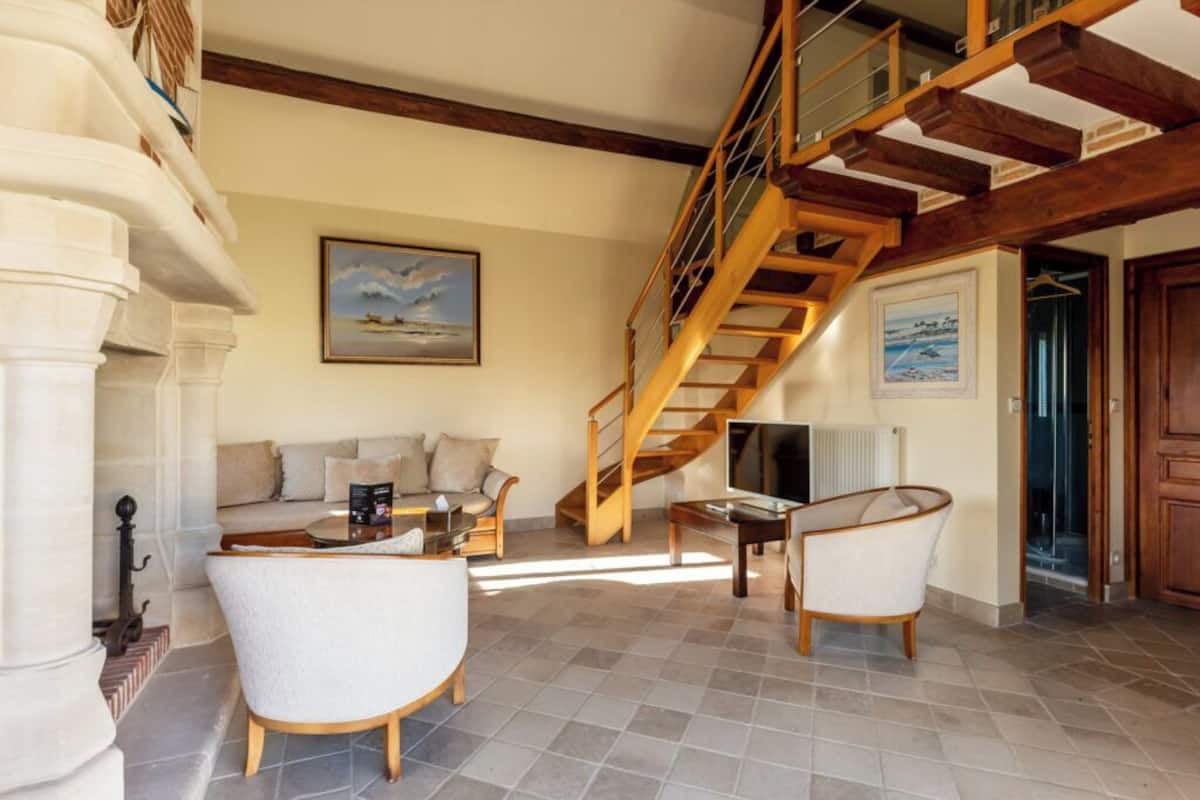 Amplia sala de estar con escalera de madera, un conjunto de sofás y una mesa de centro.