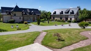 Un bâtiment traditionnel à colombages, avec un chemin de gravier et une pelouse bien entretenue.