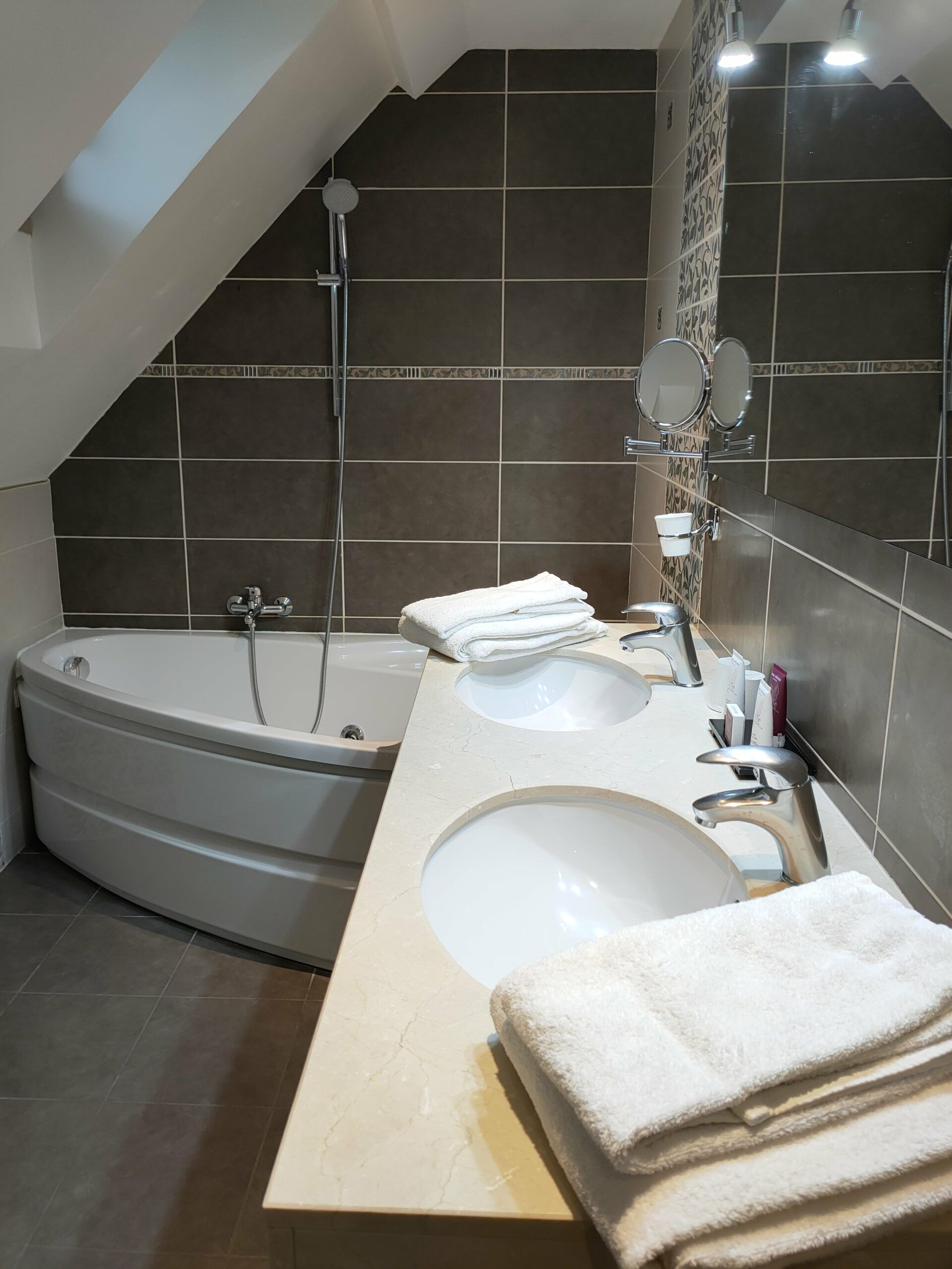 Une salle de bain moderne avec une baignoire sur pieds, deux vasques et un grand miroir.
