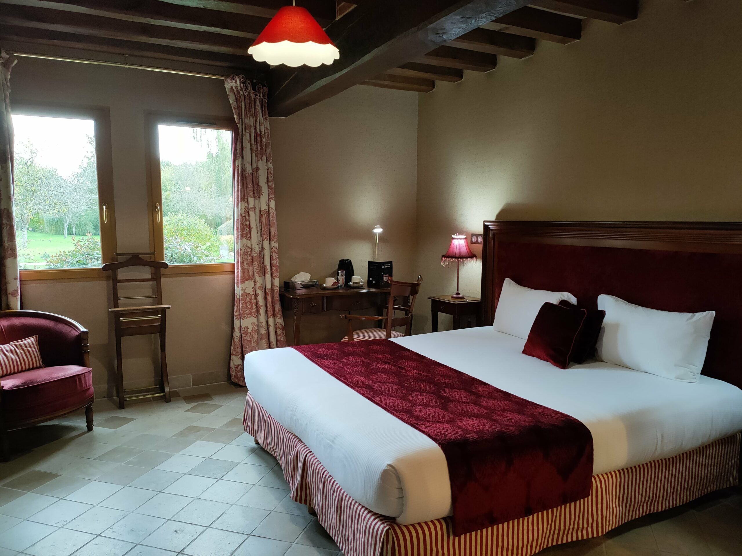 A hotel room with a large bed, a desk, a chair, and a window with curtains.