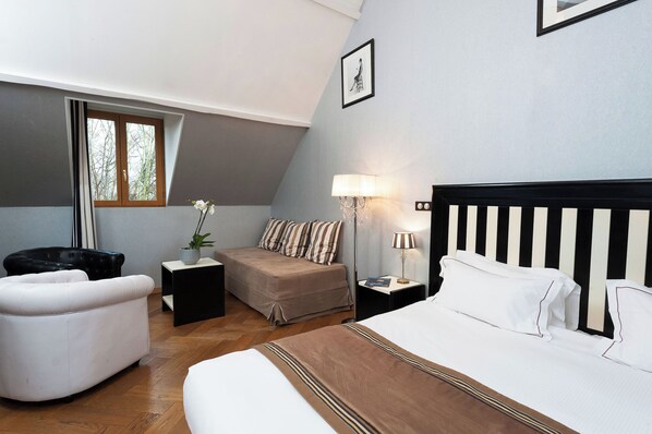 A bedroom with a bed, a chair, a nightstand, a lamp, and a window.