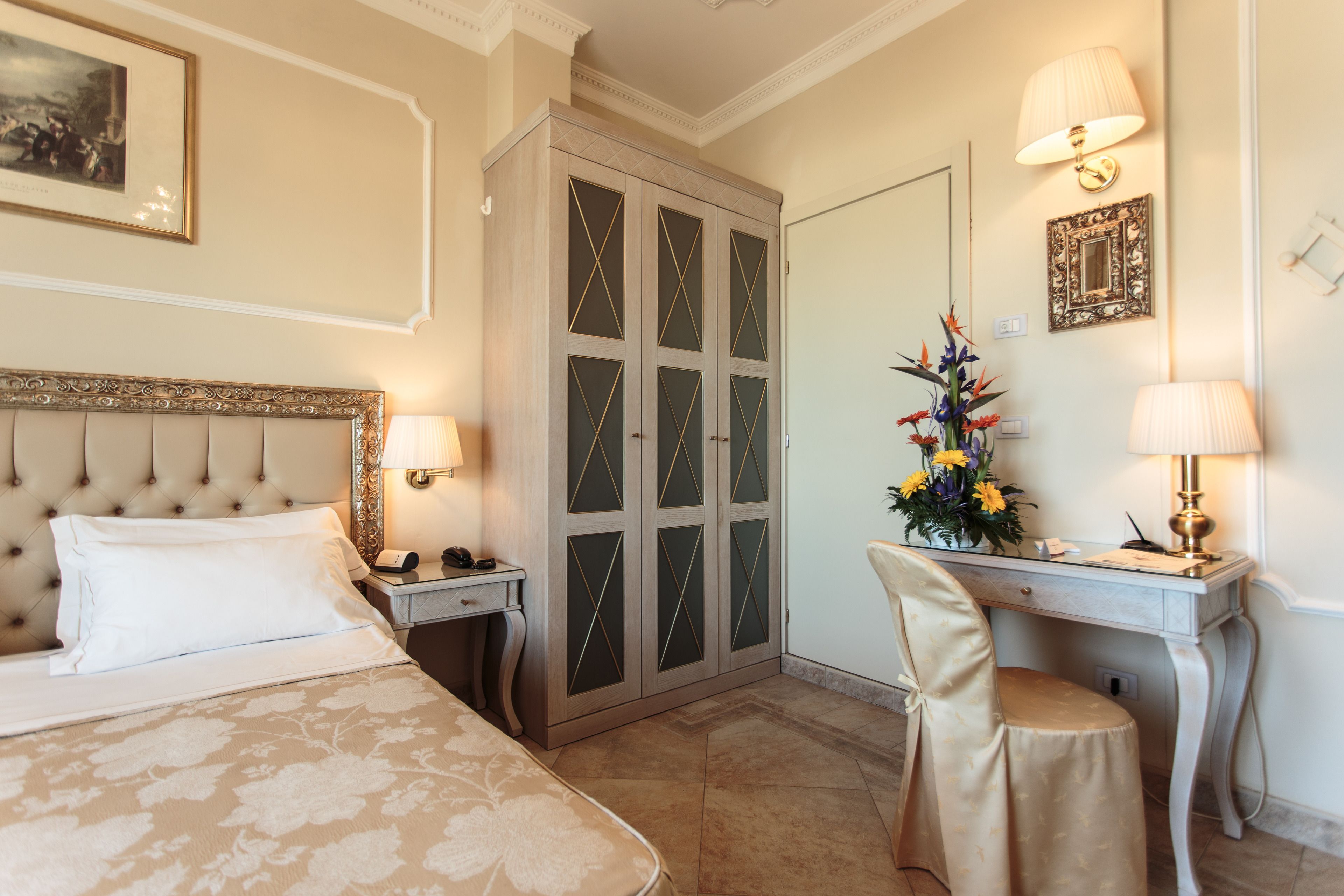 Une chambre d’hôtel comprenant un lit, un bureau, une chaise, une armoire et deux lampes.