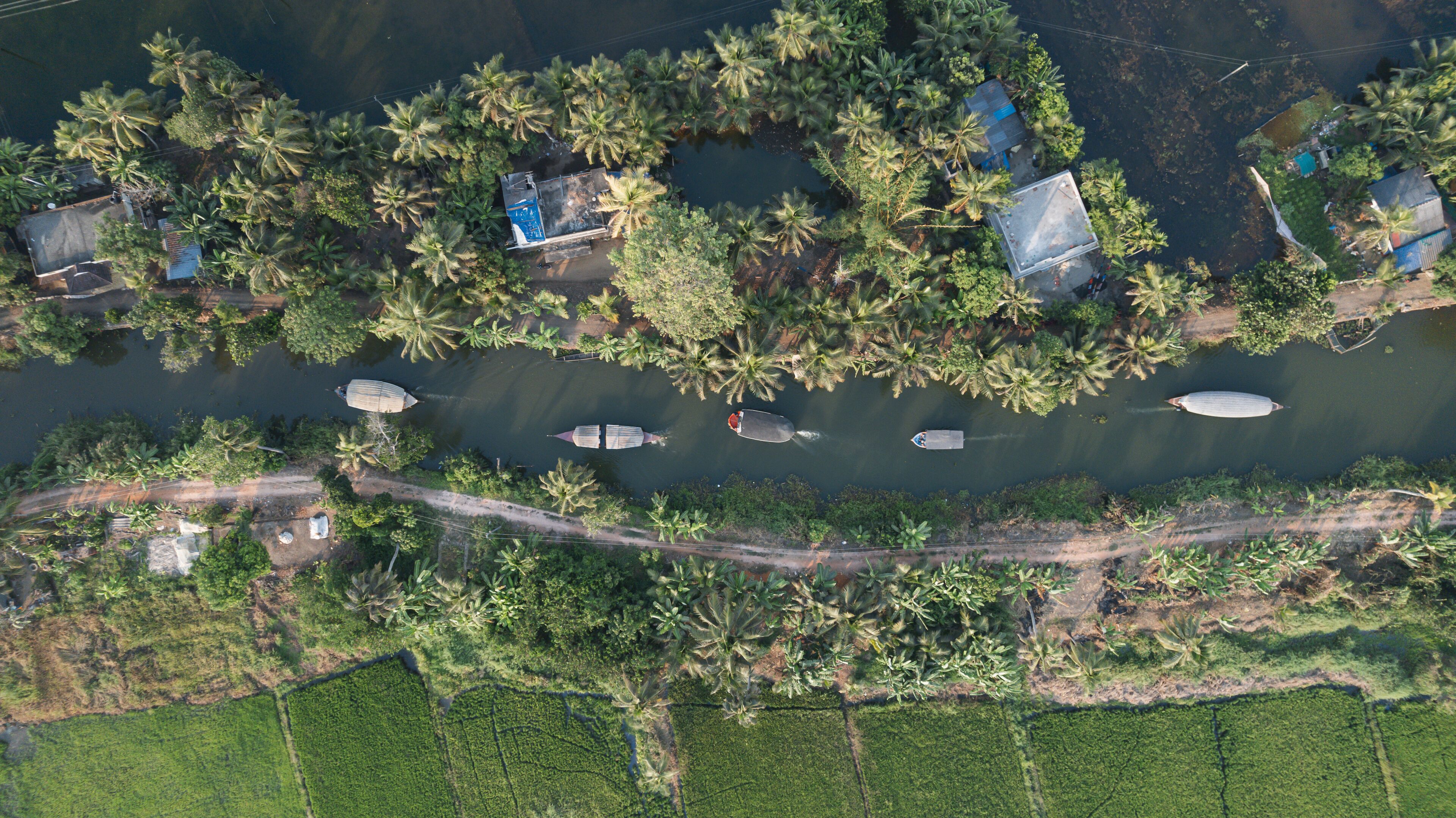An aerial view of a riverside village with houses, boats, and lush greenery.