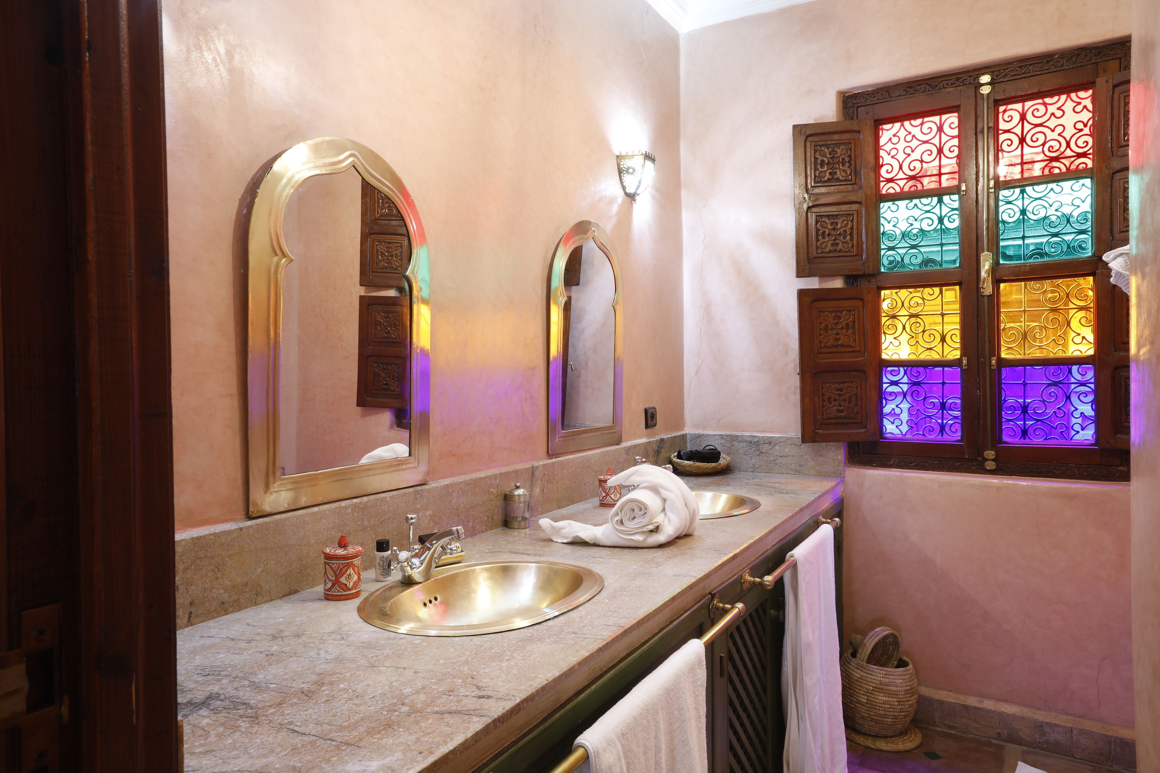 A bathroom with two sinks, a mirror, and a window with stained glass.