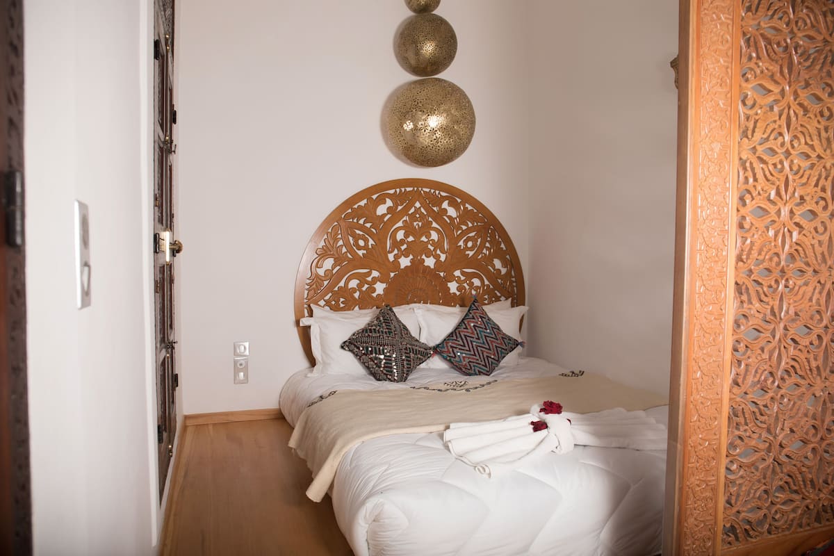 A neatly made bed with a wooden headboard, two decorative pillows, and a white blanket.