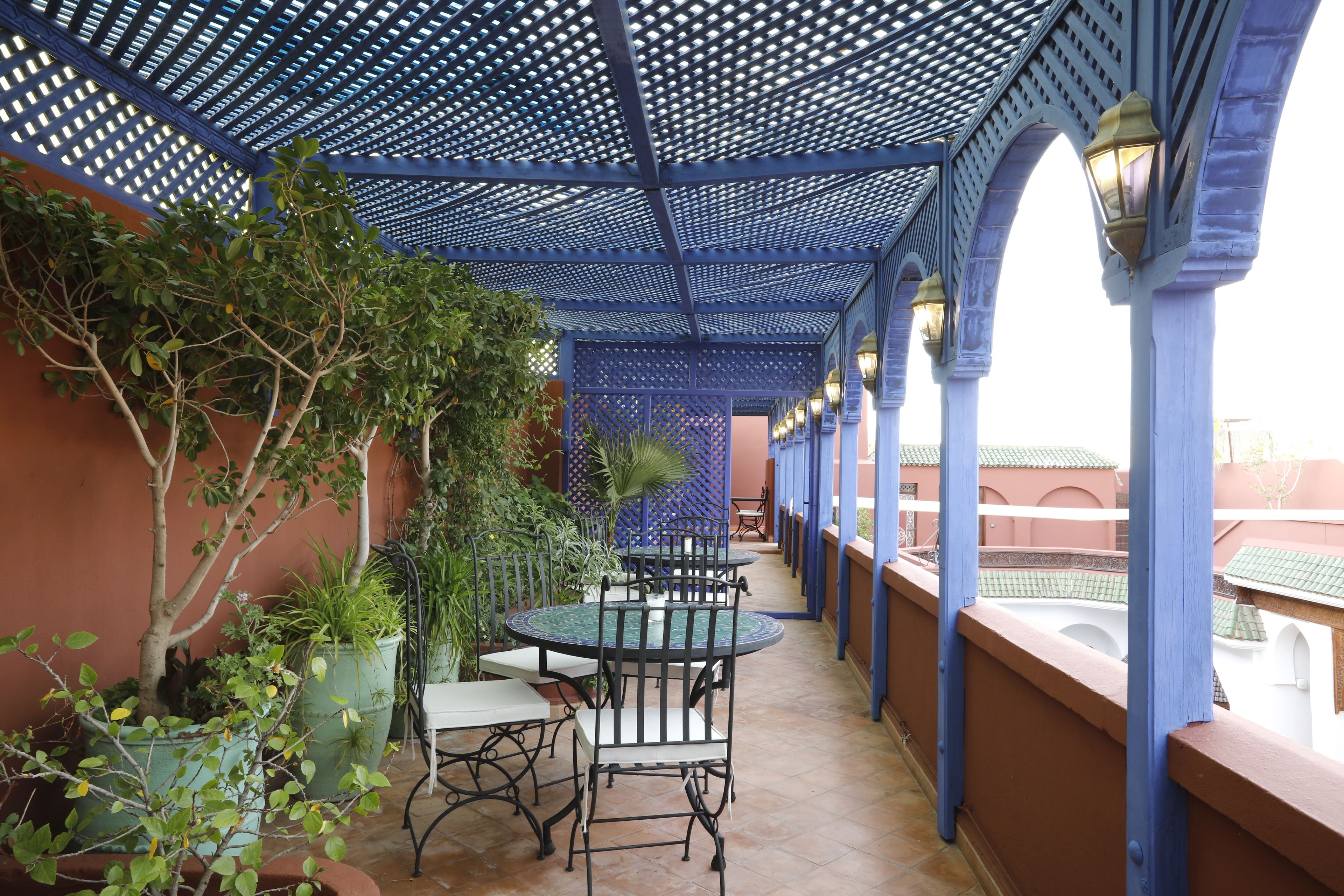 Un'area esterna coperta con soffitto blu, piante in vaso, un tavolo rotondo e sedie.