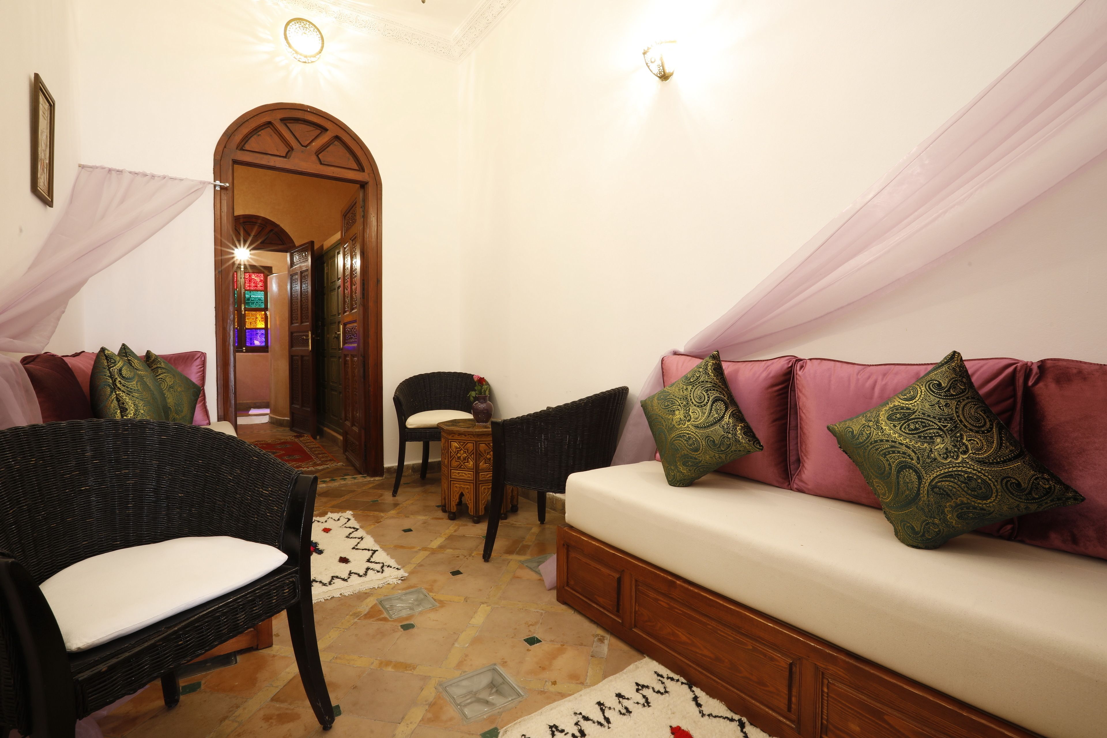 A cozy living area with a sofa, two wicker chairs, a small table, and a decorative rug.