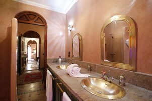 Une salle de bain avec deux lavabos, un grand miroir et une douche à l’italienne.