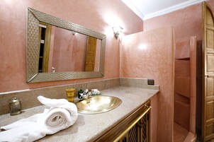 Un bagno con lavabo in marmo, uno specchio grande, un asciugamano e una cabina doccia.