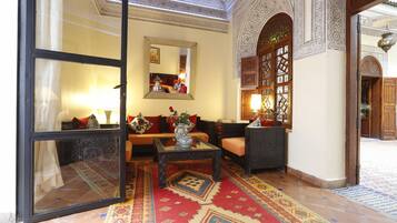 Un interior tradicional con un sofá, sillones, una mesa de centro y una alfombra estampada.