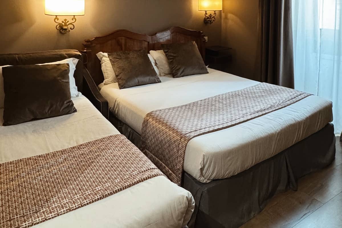 A hotel room with two beds, a painting on the wall, and two bedside lamps.