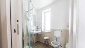 A modern bathroom with a glass shower, a sink, a bidet, and a toilet. - Albergo Santa Maria (Chiavari)