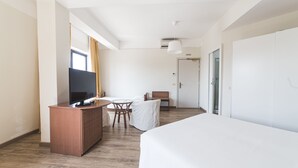 A hotel room with a large bed, a desk with a TV, a chair, and a small table. - Albergo Santa Maria (Chiavari)