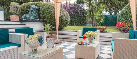 An outdoor patio with wicker furniture, a glass table, and a checkered floor.