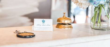 Una mesa de recepción con una tarjeta de presentación, un timbre y un florero.