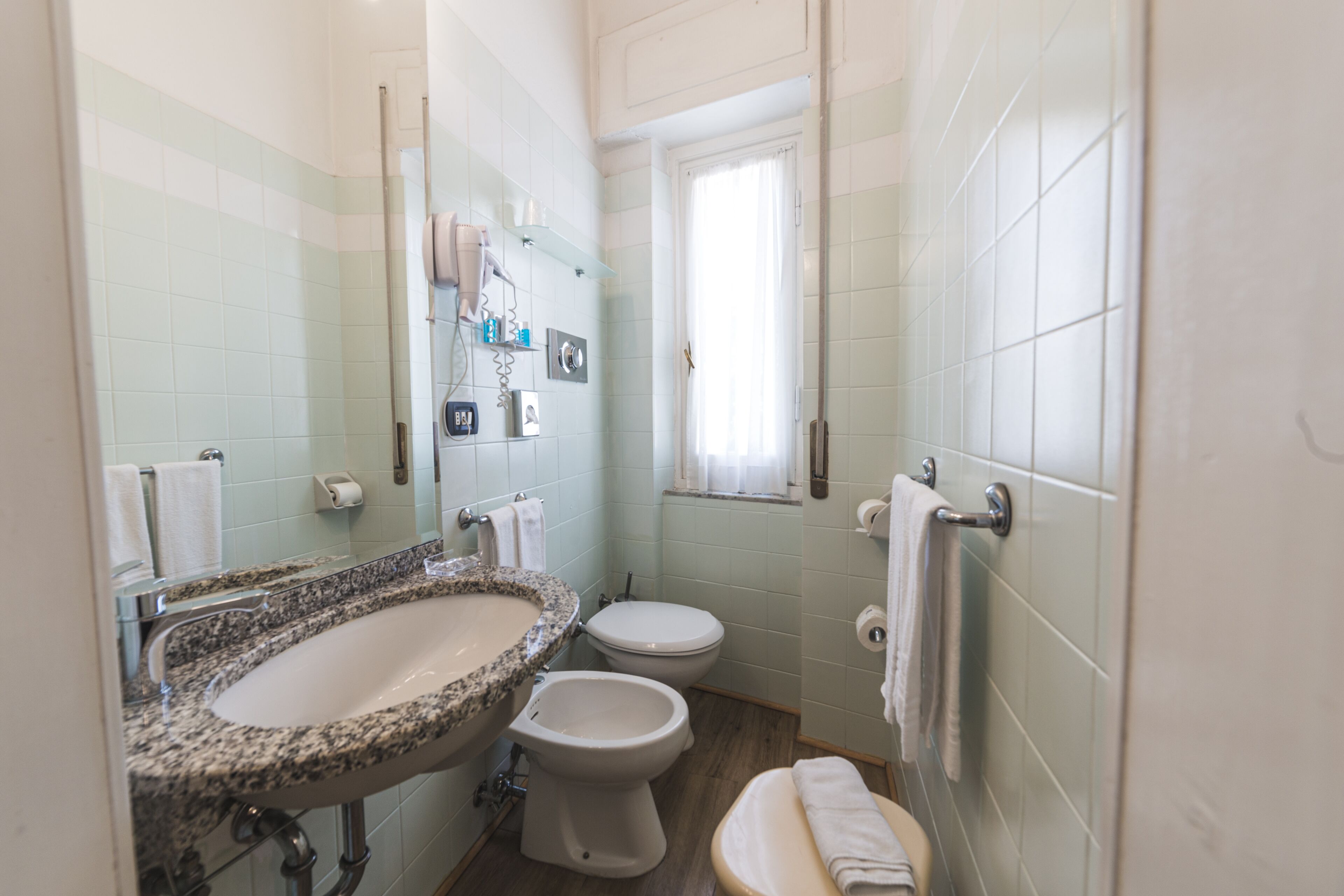 Un baño con lavamanos de granito, inodoro blanco y bidé.
