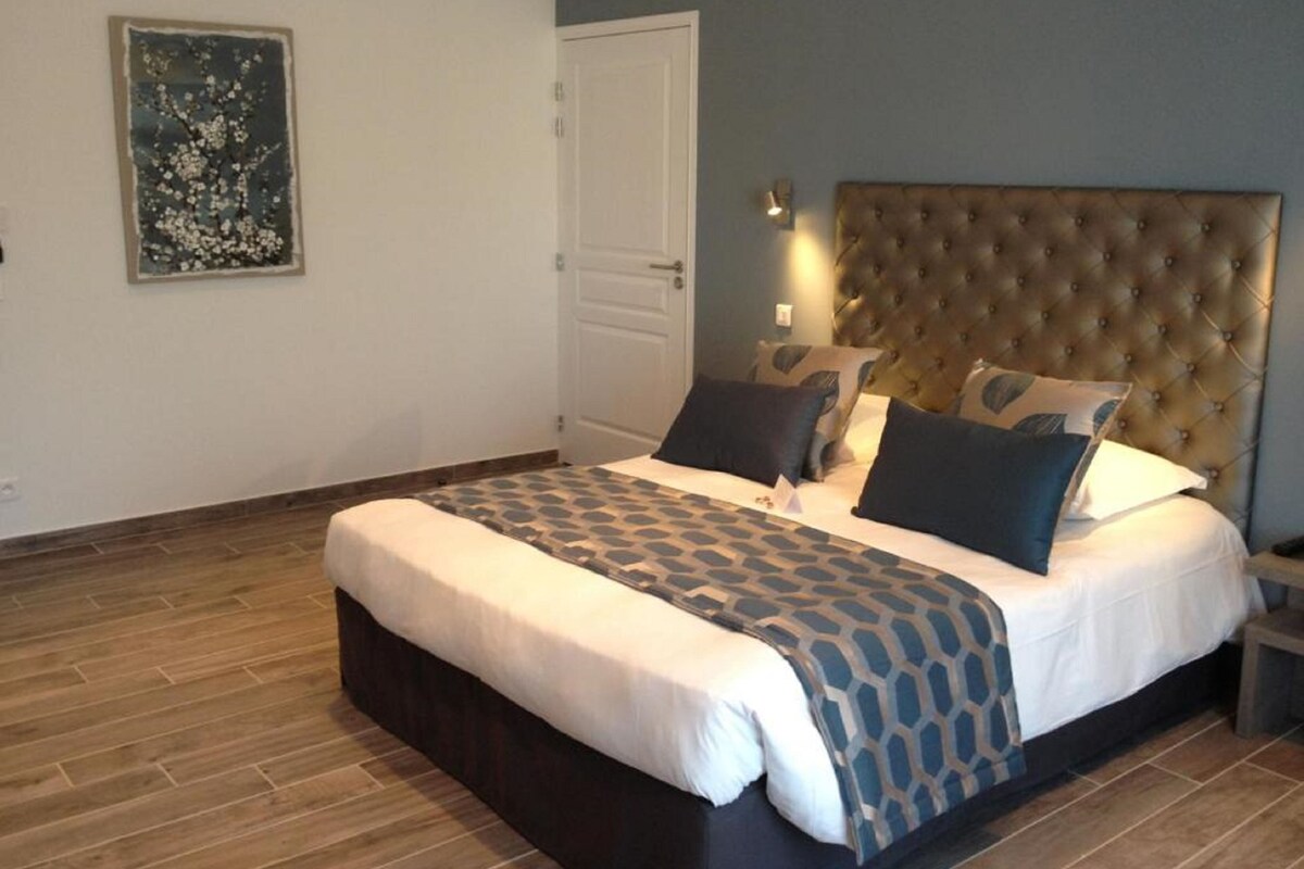 A bedroom with a large bed, a tufted headboard, and a door.