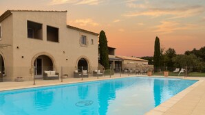 A swimming pool with a clear blue water surface, surrounded by a tiled deck and outdoor furniture. - Val Baussenc, The Originals Relais (Maussane-les-Alpilles)