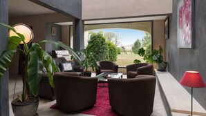 A modern living room with brown sofas, a glass coffee table, and potted plants. - Val Baussenc, The Originals Relais (Maussane-les-Alpilles)