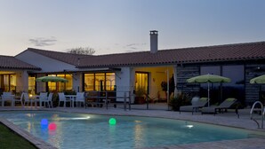 A swimming pool with a wooden deck, lounge chairs, and umbrellas.