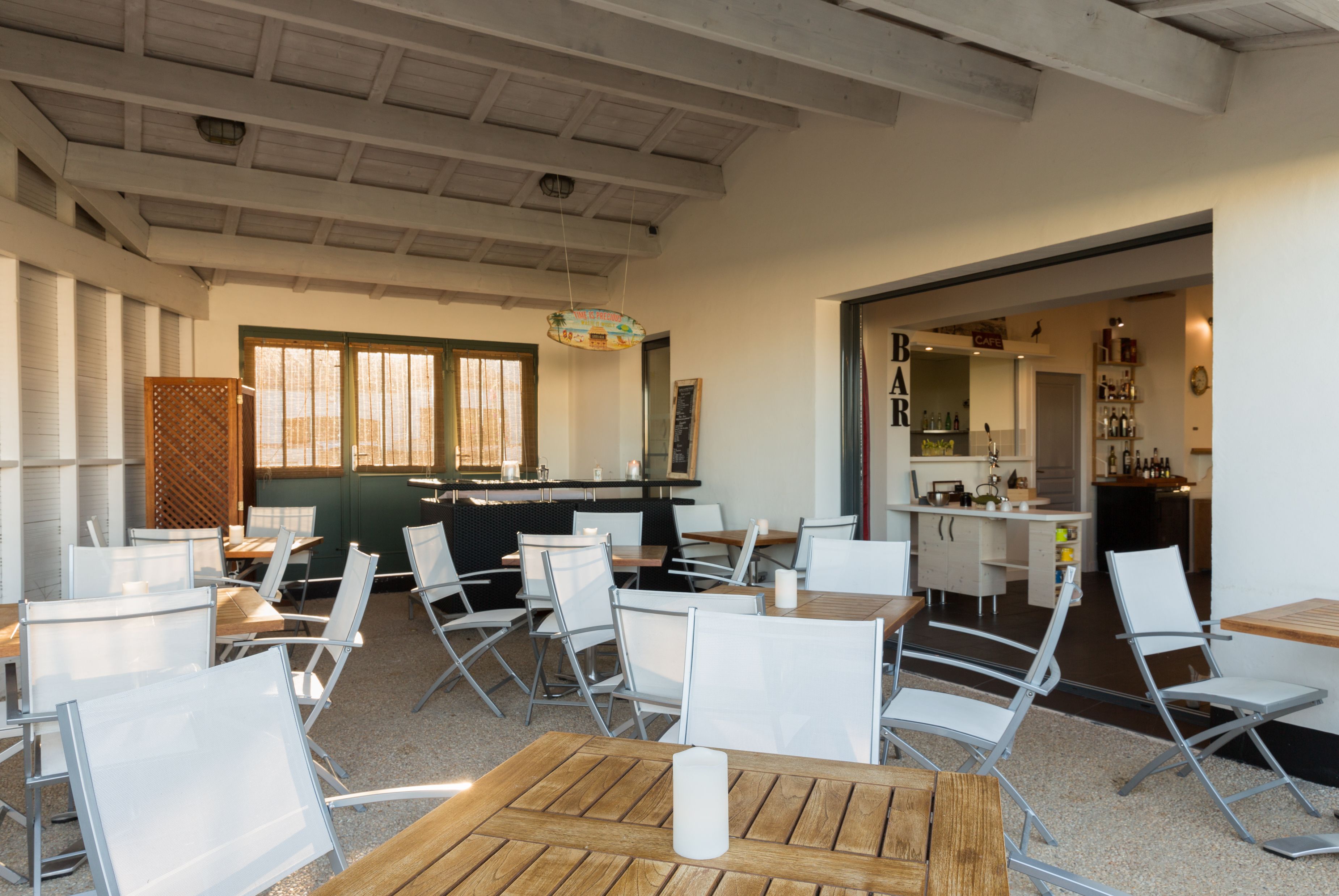 A modern restaurant interior with high ceilings, white chairs, and a bar area.