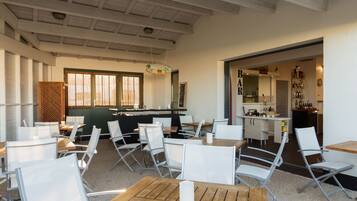 A modern restaurant interior with high ceilings, white chairs, and a bar area.