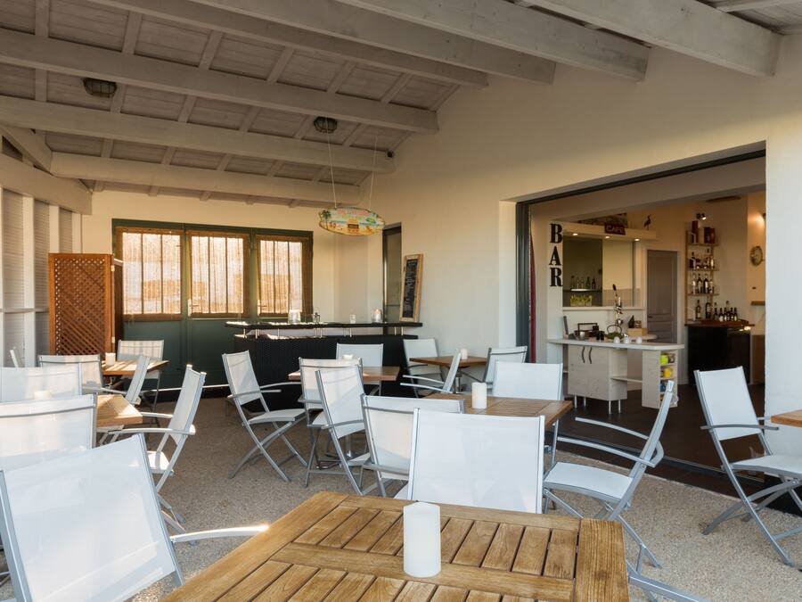 A modern restaurant interior with high ceilings, white chairs, and a bar area.