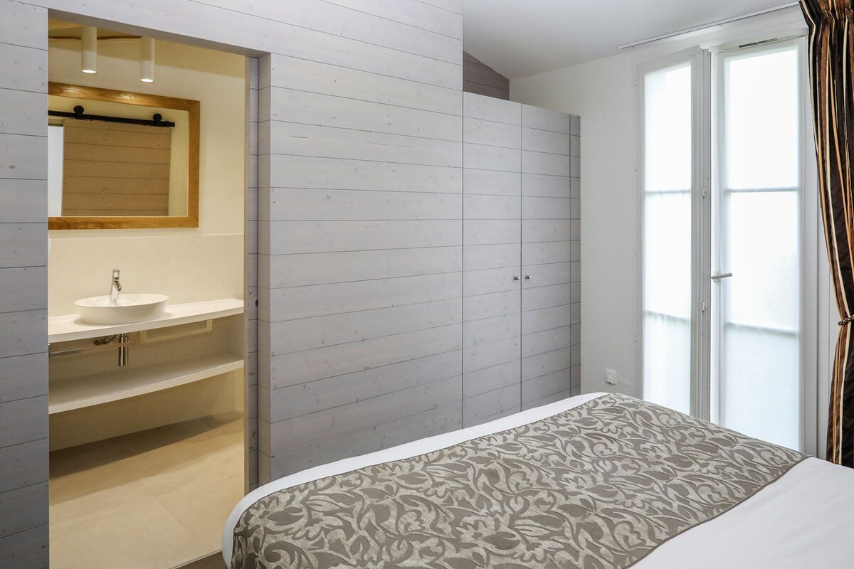 A bedroom with a bed, a bathroom with a sink, and a wardrobe.