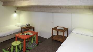 Ein Zimmer mit zwei Betten, einem kleinen Tisch mit Hocker und einem Nachttisch.