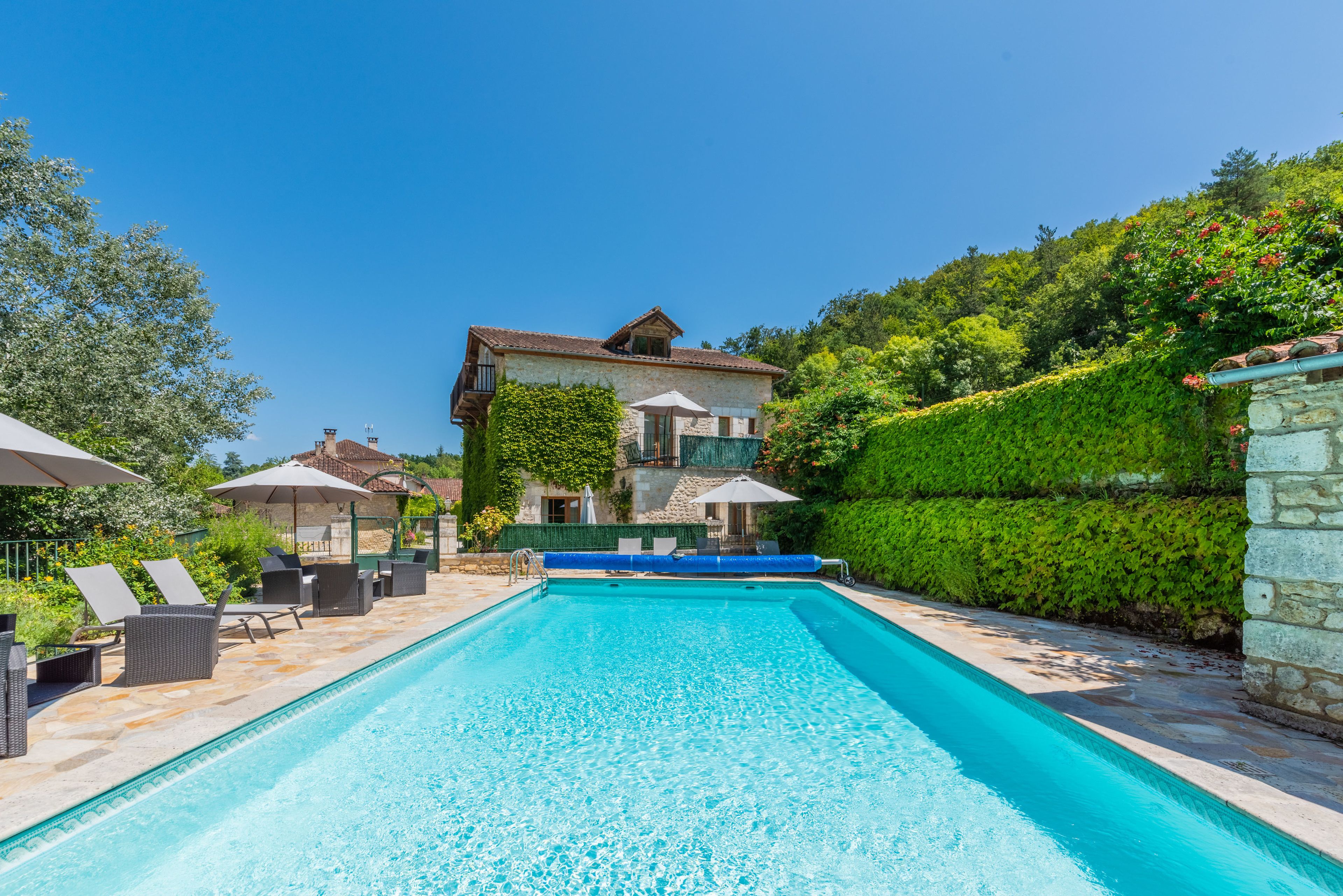 Een buitenzwembad, parasols bij het zwembad en ligstoelen