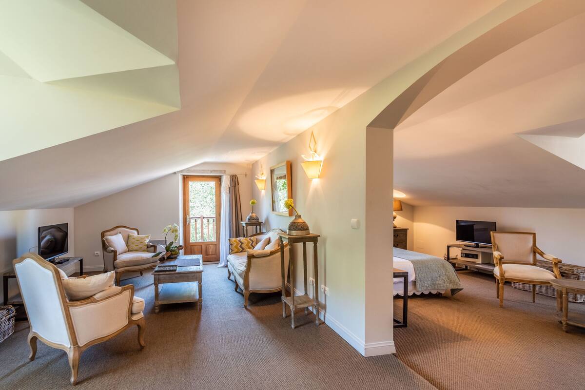 A cozy, well-lit living room with a high ceiling, a television, comfortable seating, and a small table.