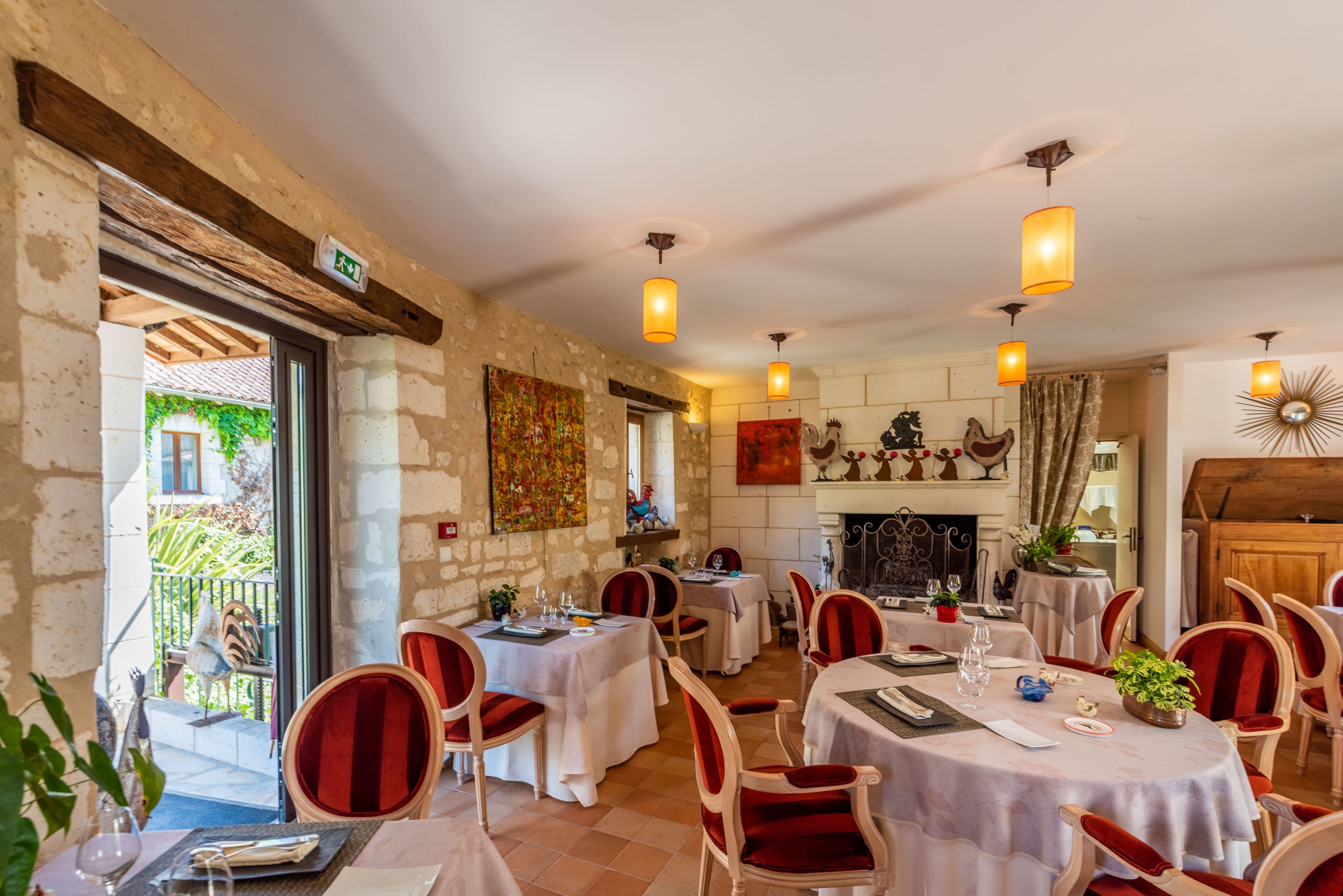 Een restaurant met meerdere tafels en stoelen, een open haard en uitzicht op buiten.