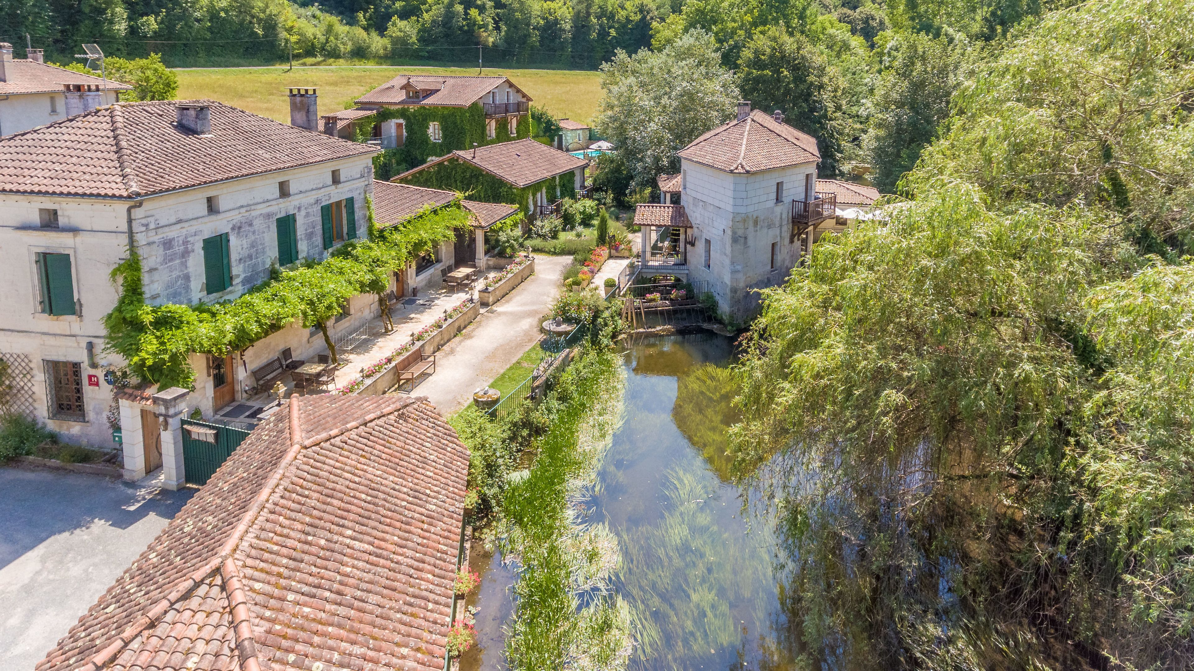 A riverside village with traditional buildings, a narrow canal, and lush greenery.