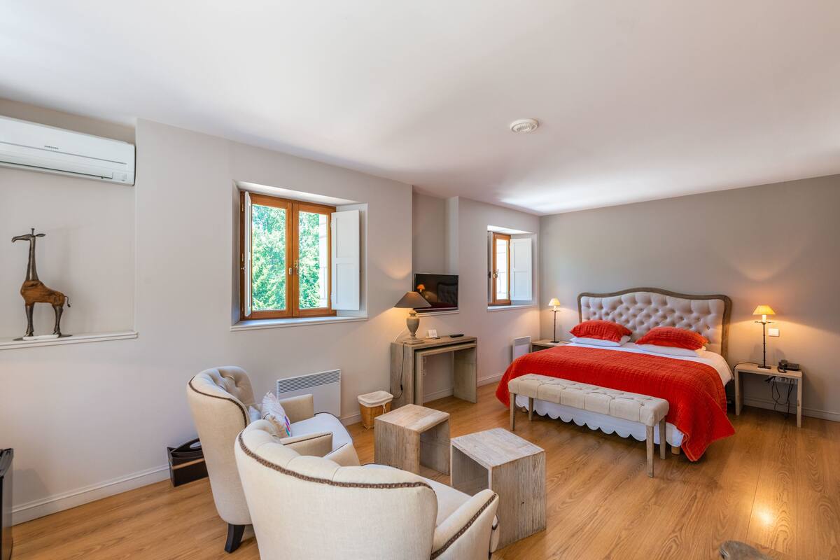 A bedroom with a bed, bedside tables, a TV, and a window.